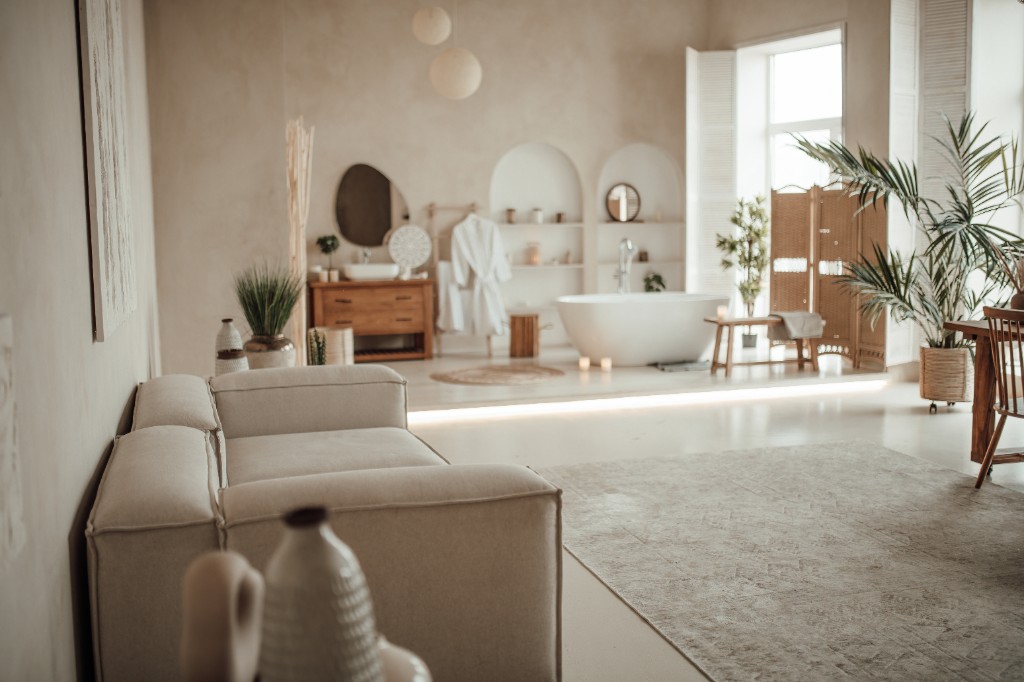 A serene spa-like bathroom and lounge with a freestanding soaking tub, warm natural light, and neutral tones