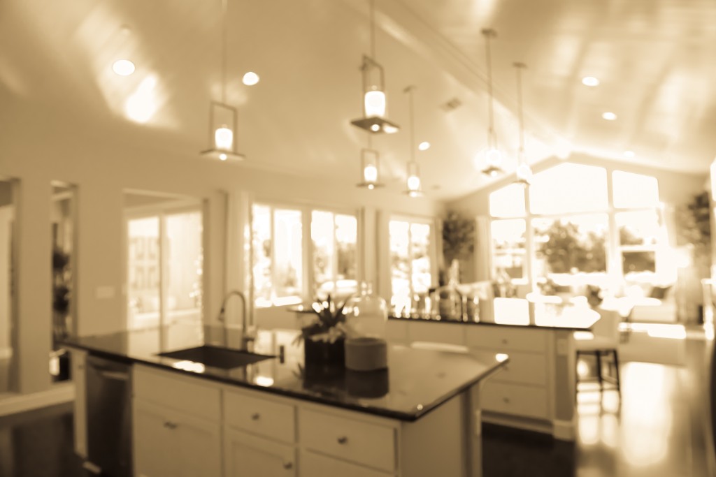 A warm, sun-drenched modern kitchen with a large island and pendant lighting, creating an inviting premium home atmosphere