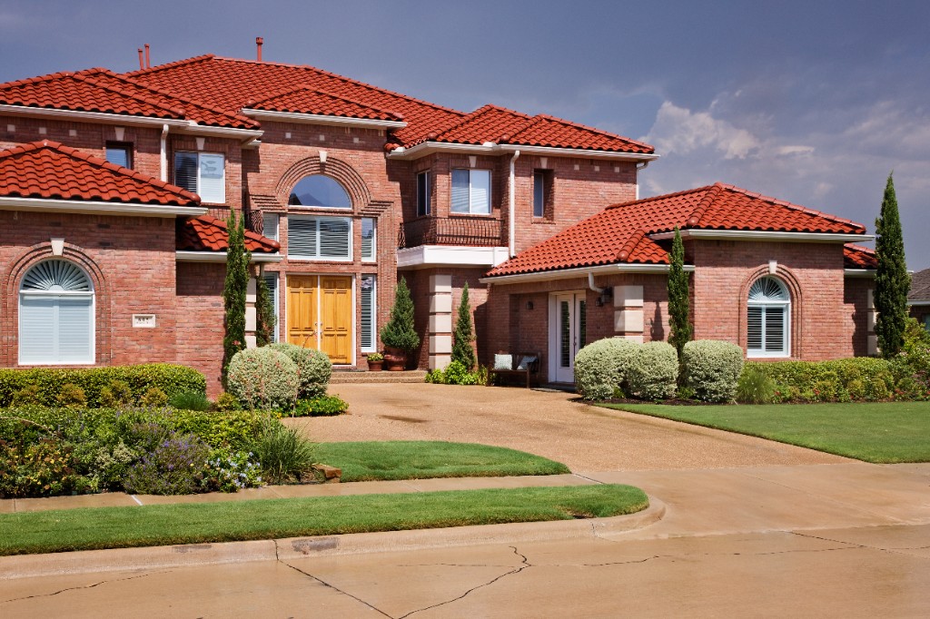 A welcoming suburban home with a red clay tile roof, brick exterior, and manicured front landscaping